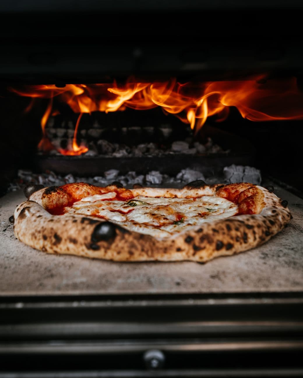 Pizza im Holzofen der Trattoria Lume, Flammen im Hintergrund